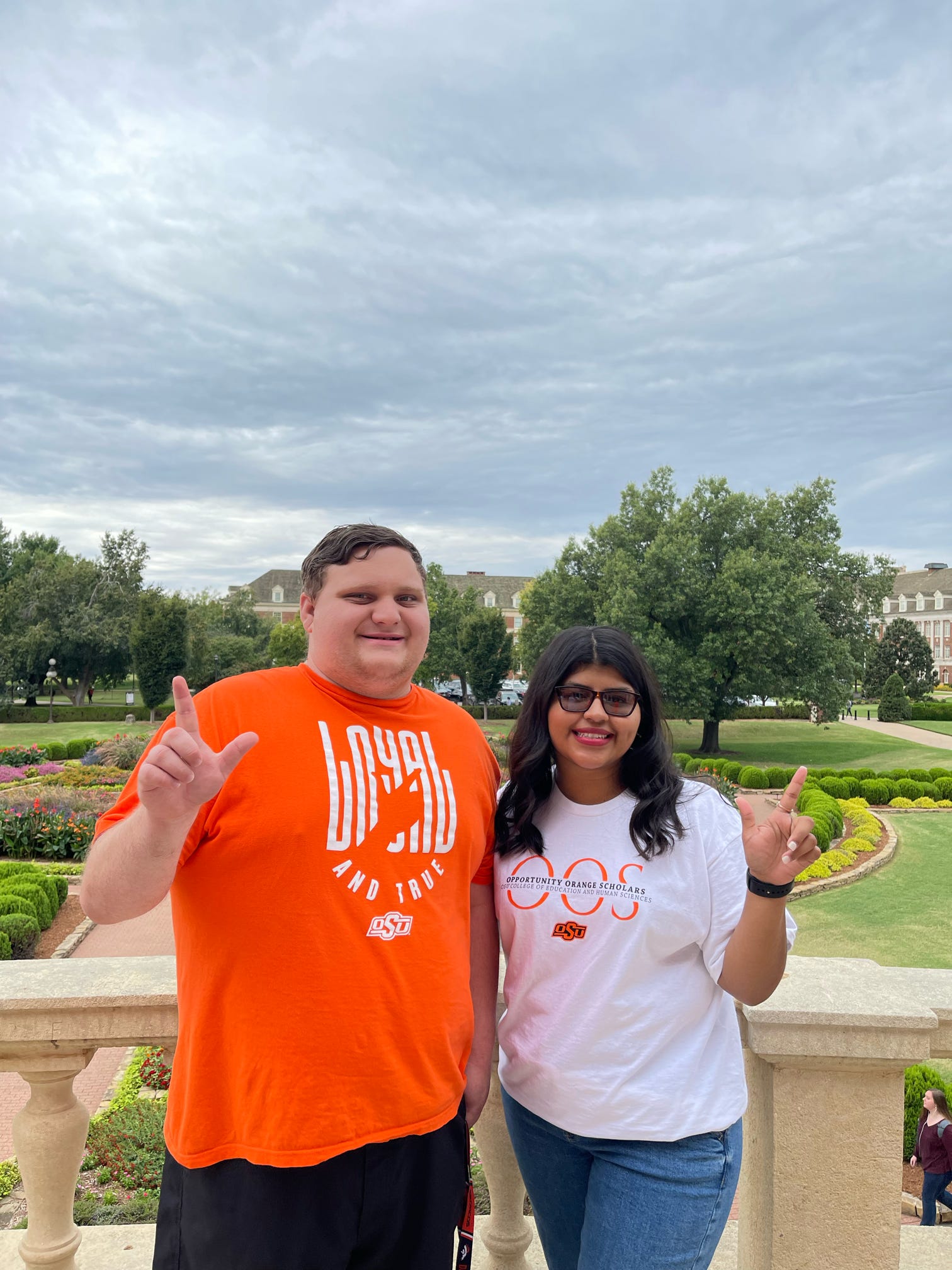 OOS students pose on campus with the "Go Pokes" hand signal