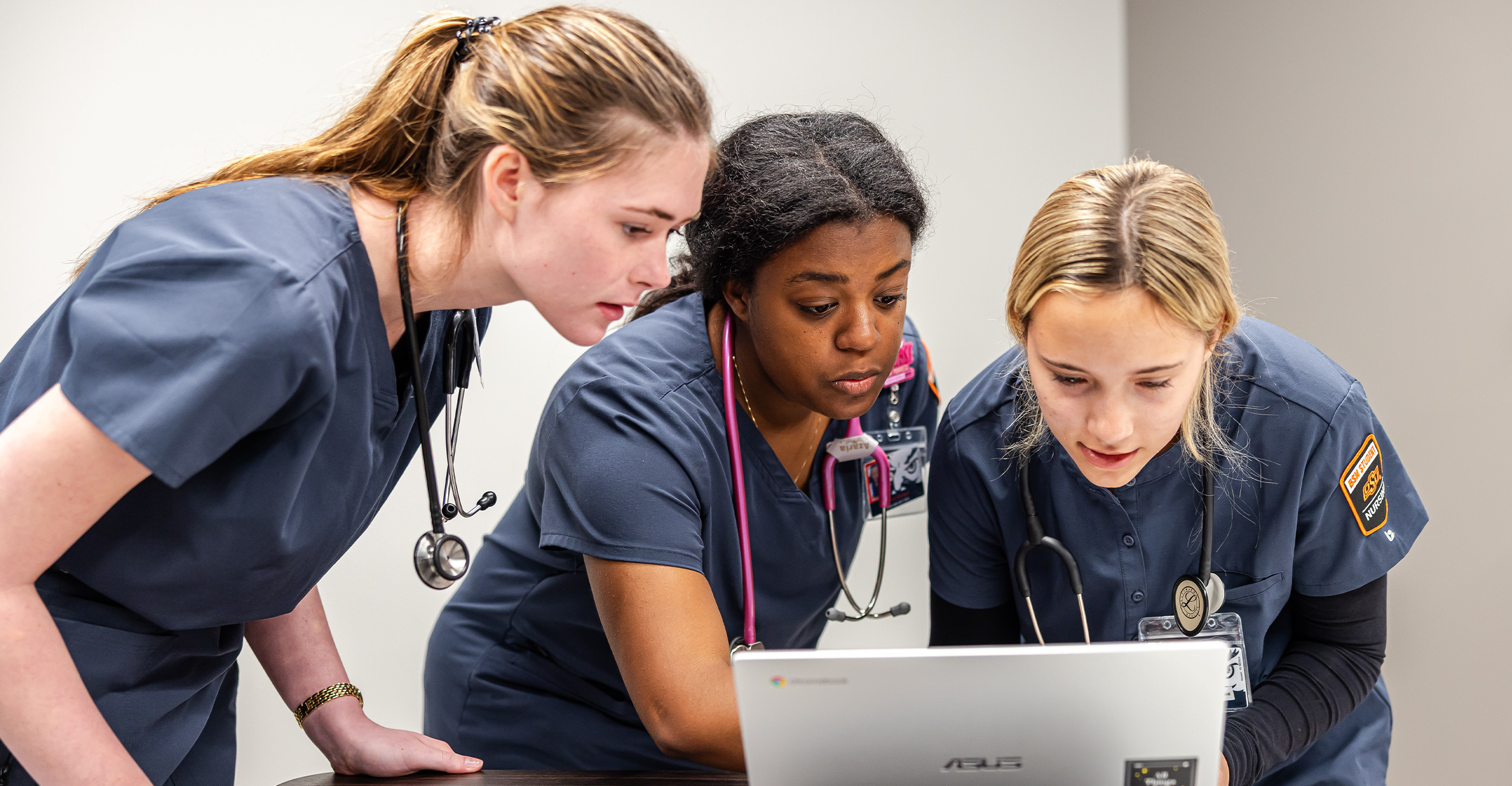 OSU Nursing students look overtop a computer