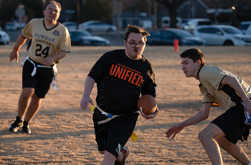 OSU Unified team member runs with ball during game of flag football against competing Purdue University team