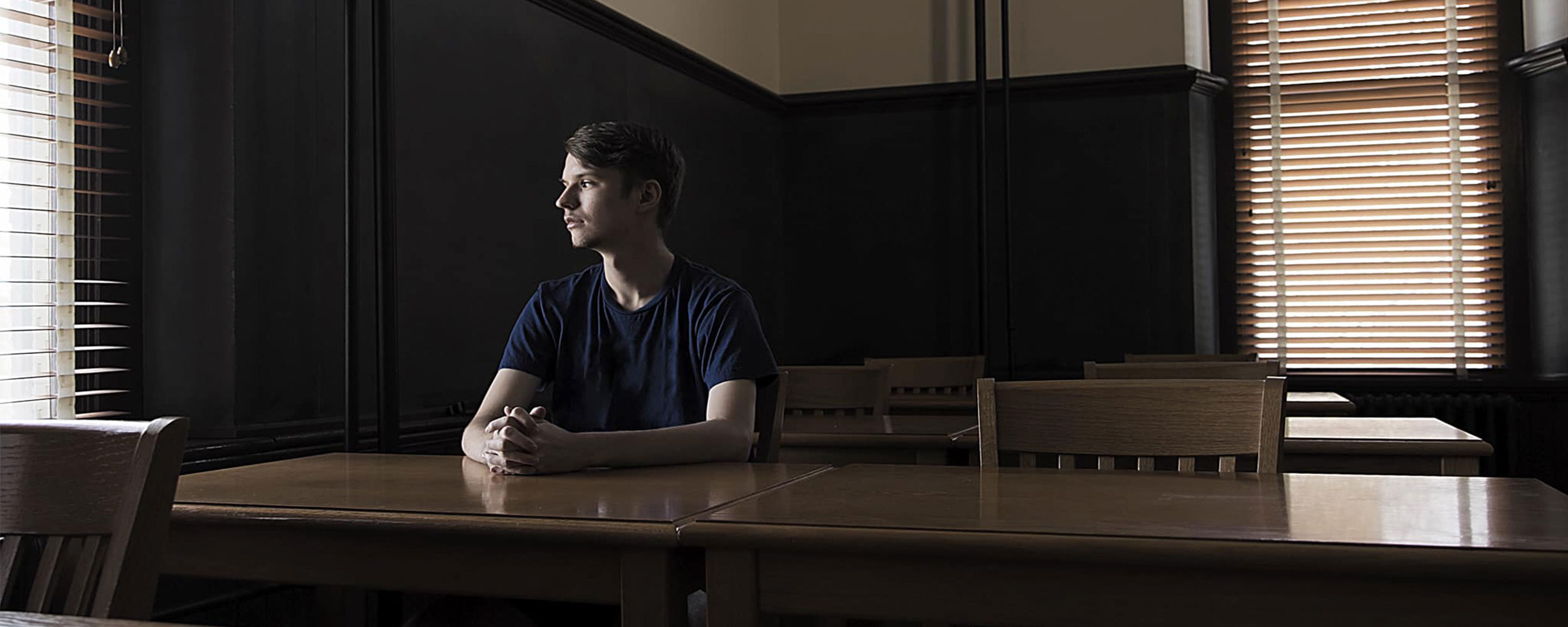 Student Dima Sholom sits at table looking out a window