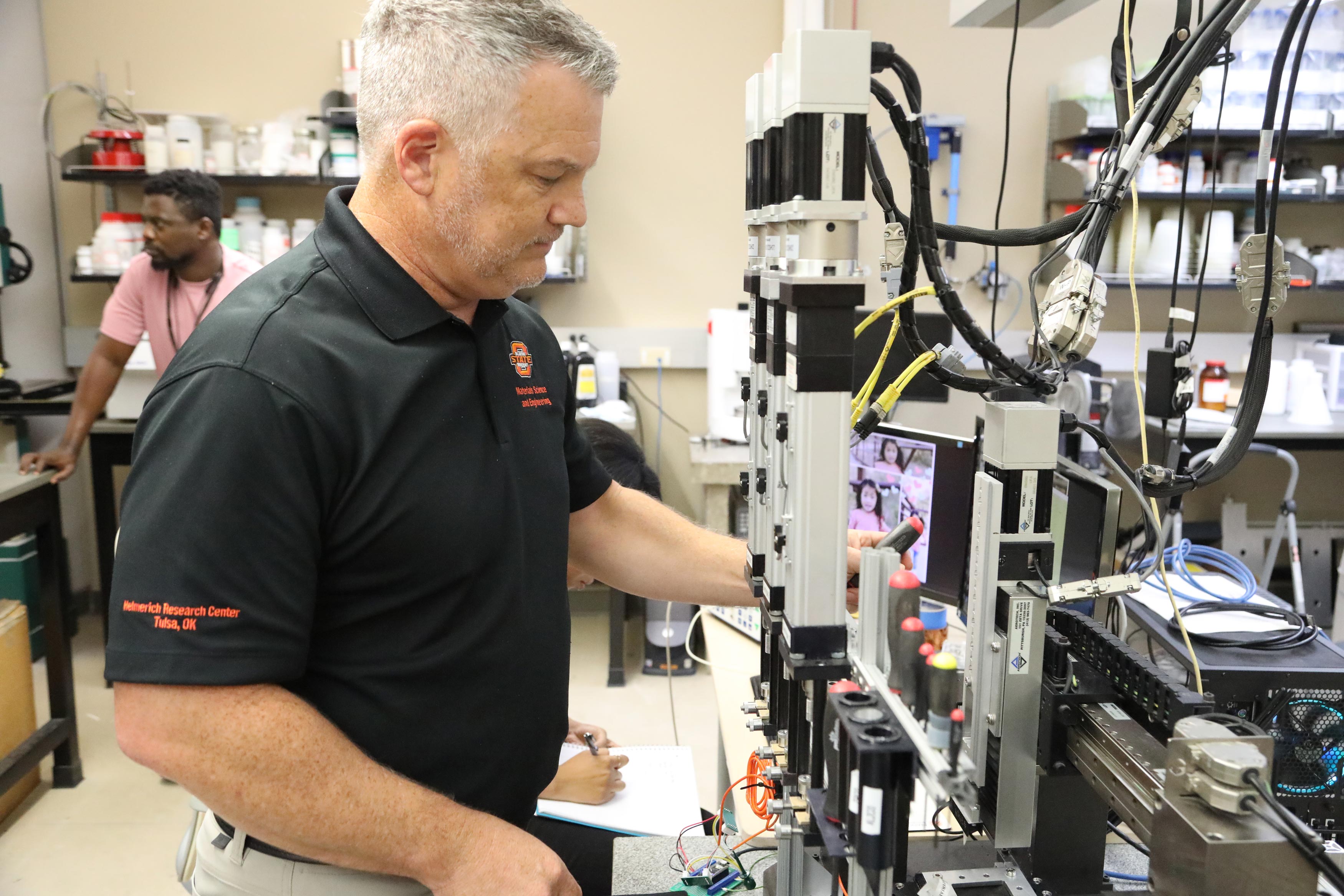 Dr. Jim Smay checks the test apparatus before beginning a test run using a great white shark tooth.