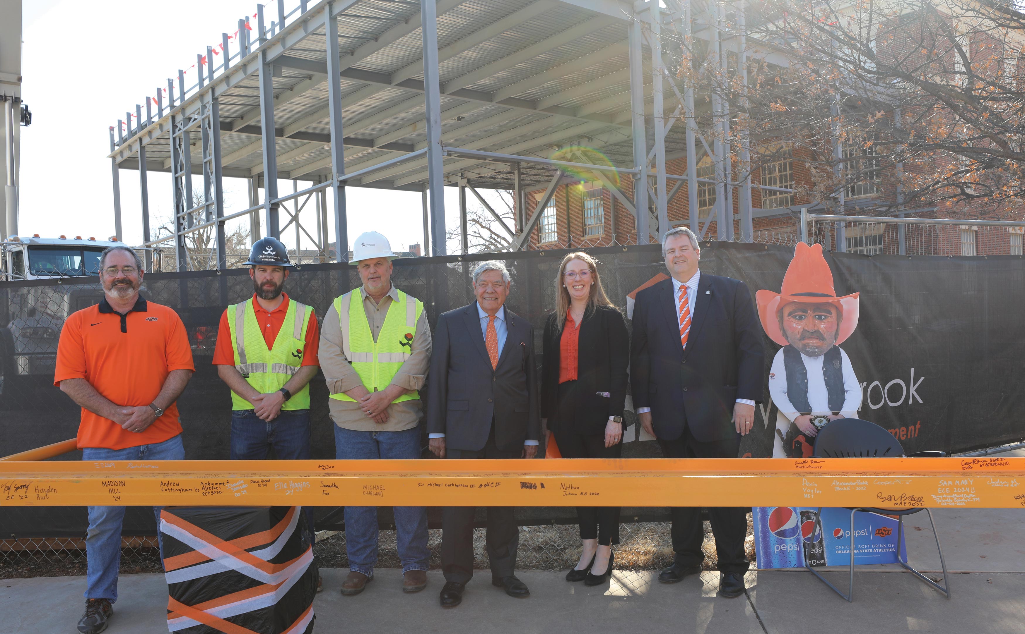 From left: CEAT Facilities Manager Patrick Wheeler, CMS Willowbrook Director of Operations Bryan Miles, CMS Willowbrook Project Superintendent Wayne Leatherbury, Representative of the Chickasaw Nation and CEAT alumnus Neal McCaleb, Provost and Senior Vice President of OSU Jeanette Mendez and CEAT Dean Paul Tikalsky stand in front of a signed beam prior to the Engineering South topping out ceremony. The beam was placed on the Chickasaw STEM Auditorium by members of the construction company, CMS Willowbrook, who worked on the building.