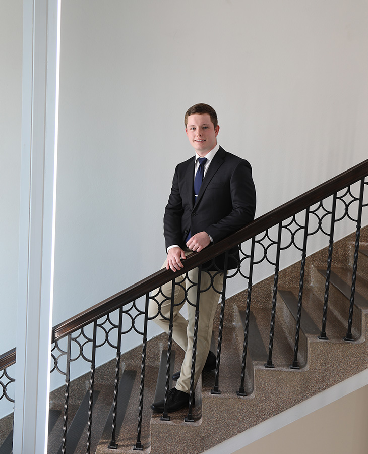 A man in a suit stands confidently on a stairway, exuding professionalism and poise.