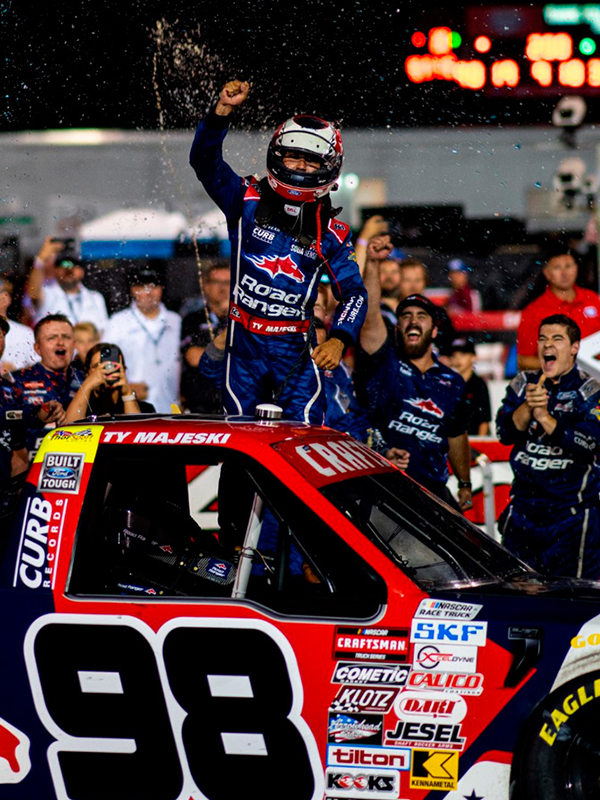 Kade and his racing team cheering on their driver in victory lane after the 98 Road Ranger wins the NASCAR Craftsman Truck Series TSport 200 at Indianapolis Raceway Park.