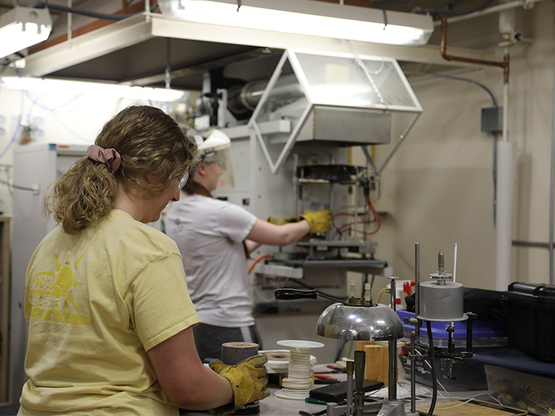 Jordan Erne prepares soil samples while Aria Hansen places them into the cone heater to collect data.