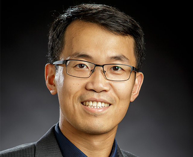 Studio Potriat of Dr. Yu Feng, smiling while wearing and gray and navy suit