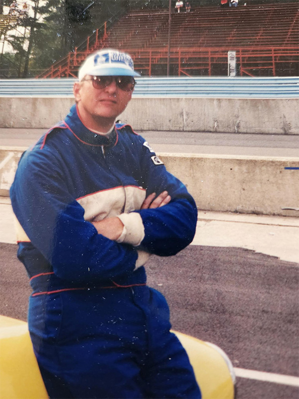 A man leaning against an older racecar.