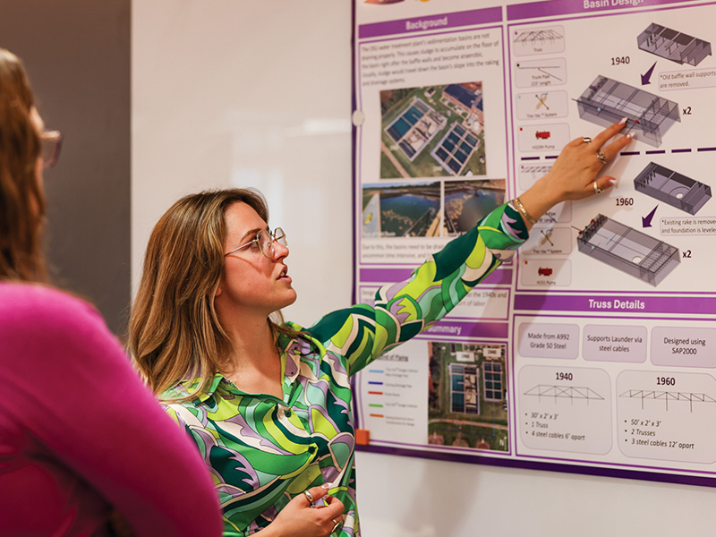 A femal student presents her research to expo attendees.
