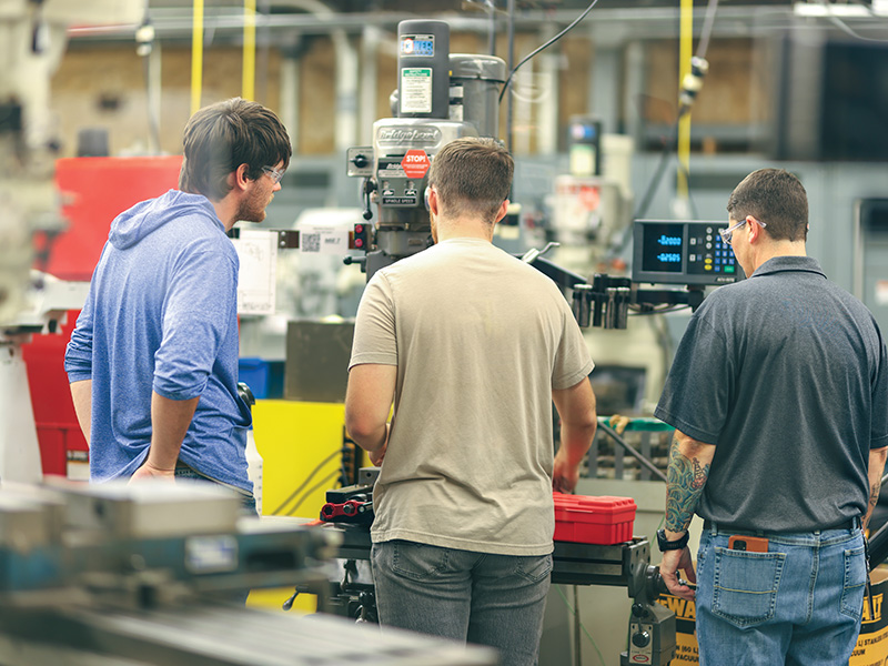 A group of people stand around equipment in a laboratory.