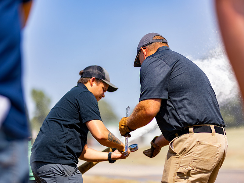 Two people work on a fire hose.