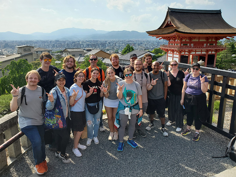 A group of people stand near a temple in Japan.