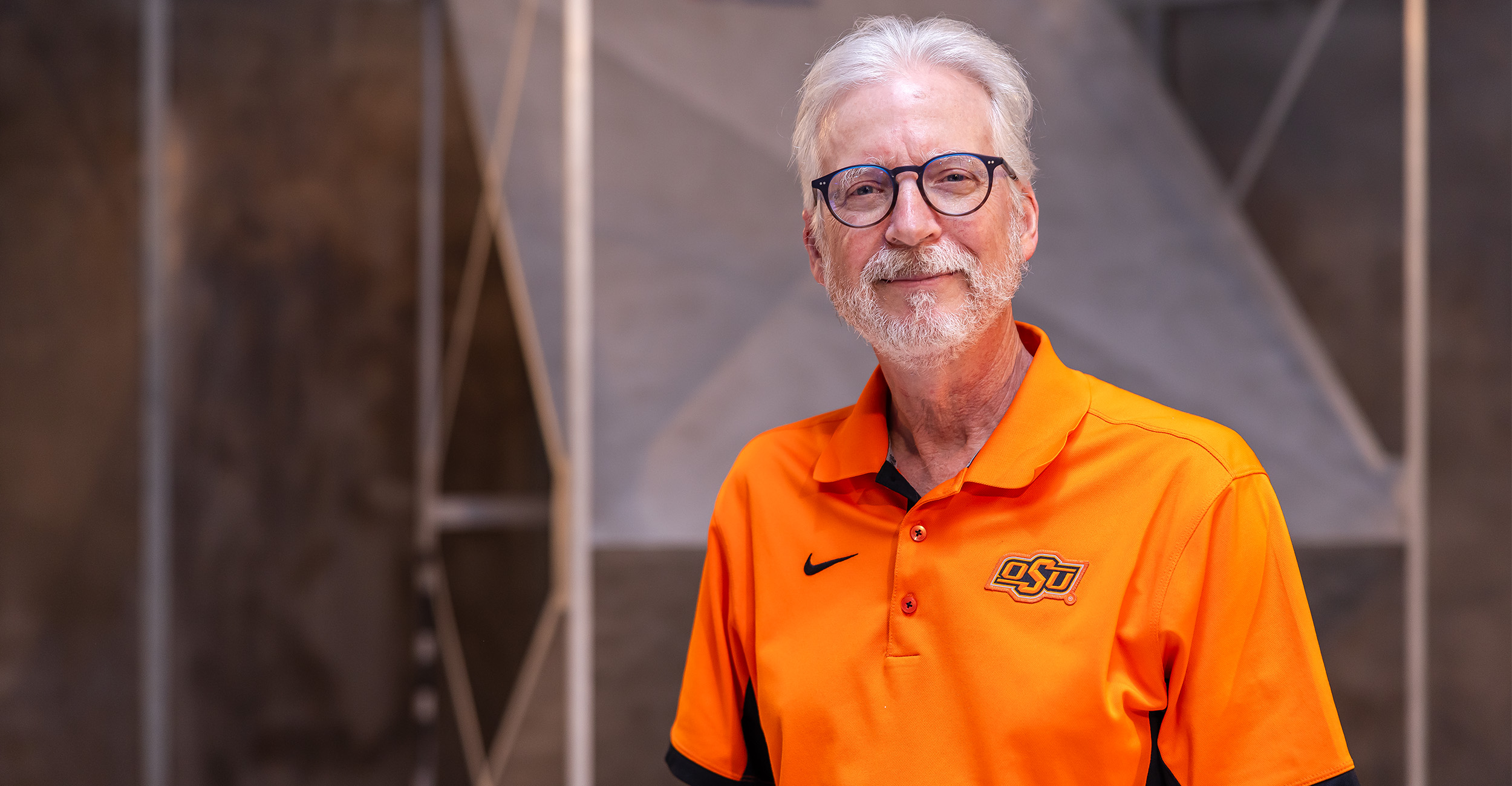 A man in an orange OSU polo stands within a reverberation chamber.