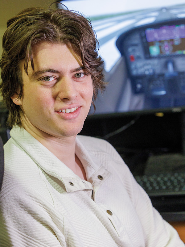 Brock Rouser sits in the seat of a flight simulator for a portrait.