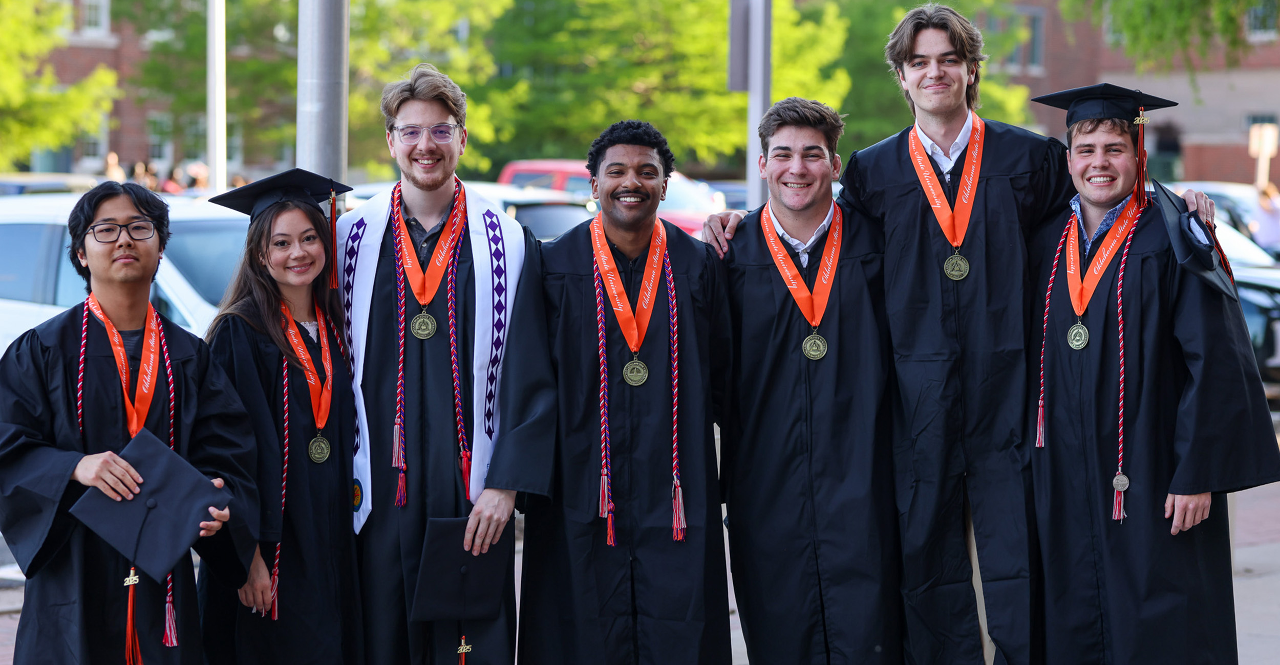 A group of graduates in full garb, posing and smiling