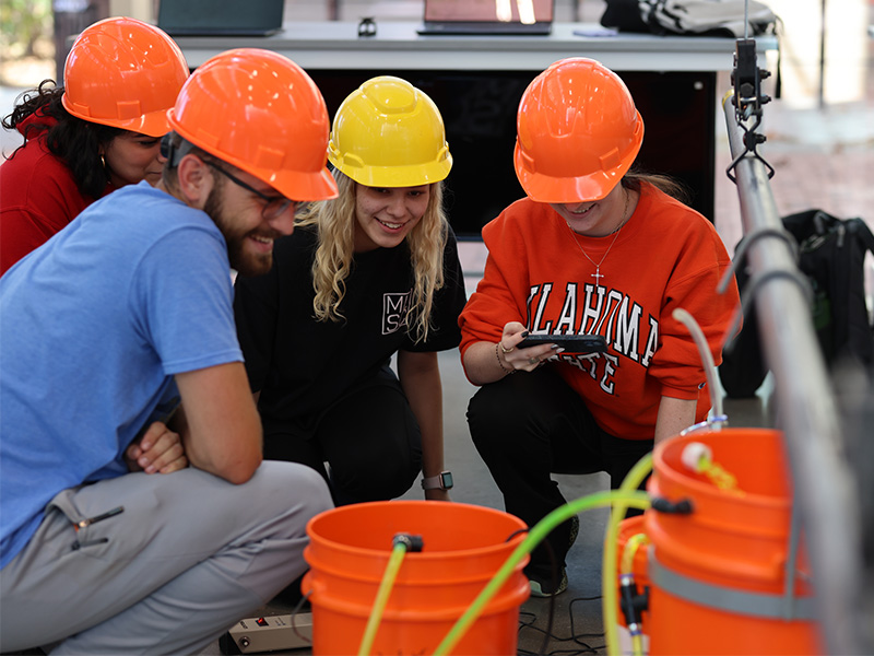 A group of students in hard hats work on a fluid flow experiment.