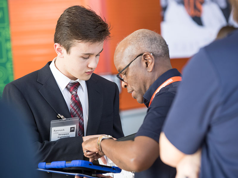 A young man in a suit shows his resume to a recruiter.