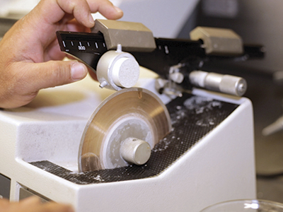 A slow-action diamond saw is used to section filter discs from a bulk composite ceramic cylinder.