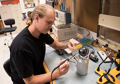 Graduate student Bryan Hayes works on an Active Tissue Equivalent Dosimeter (ATED) at Oklahoma State University's Venture 1 labs. An ATED, which measures cosmic radiation, flew on the International Space Station over the summer.