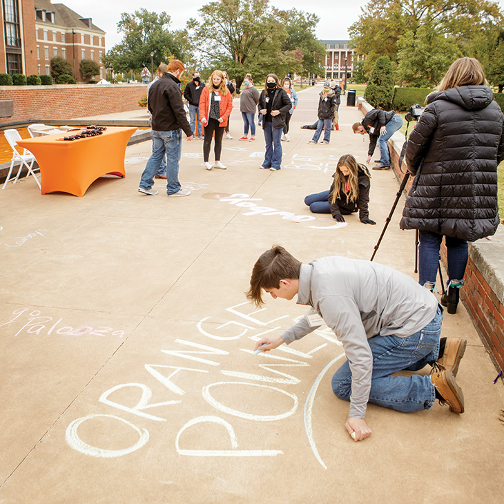 Students add some school spirit to the sidewalk in front of Edmon Low Library during Pokes Palooza.