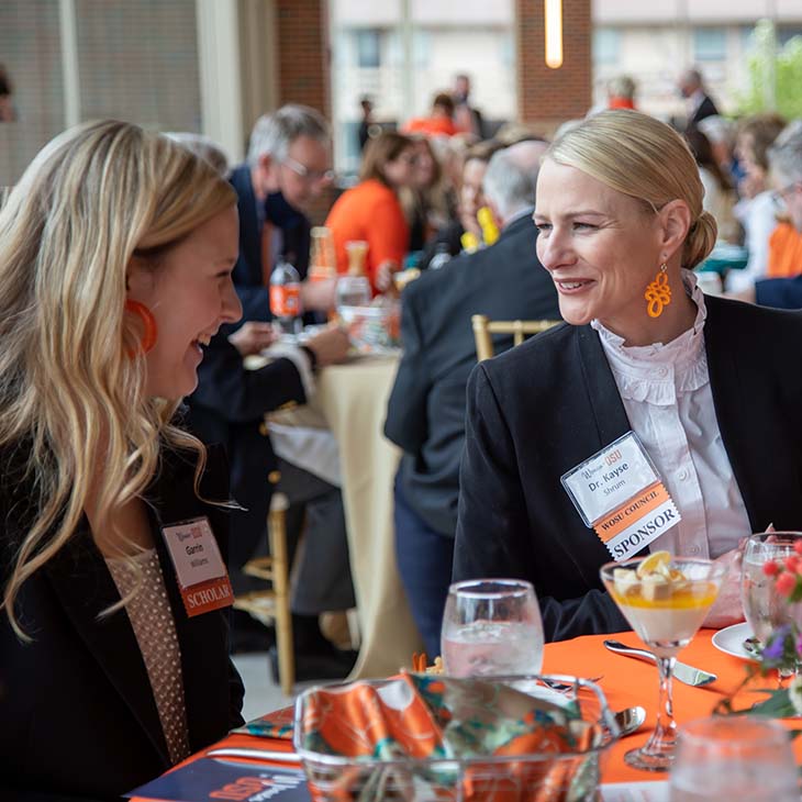 osu president kayse shrum talking with a student at the symposium