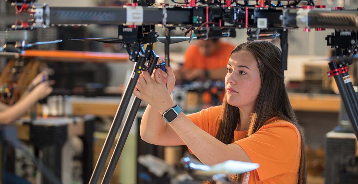 A female OSU student working on a piece of aerospace equipment.