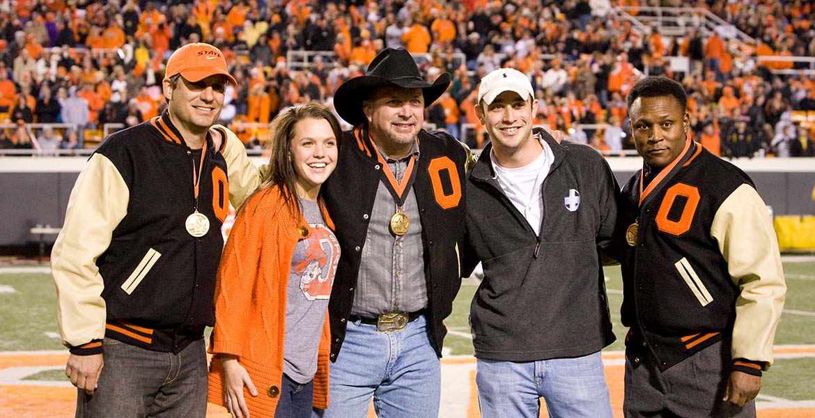 Garth Brooks, Barry Sanders and Robin Ventura on the football field