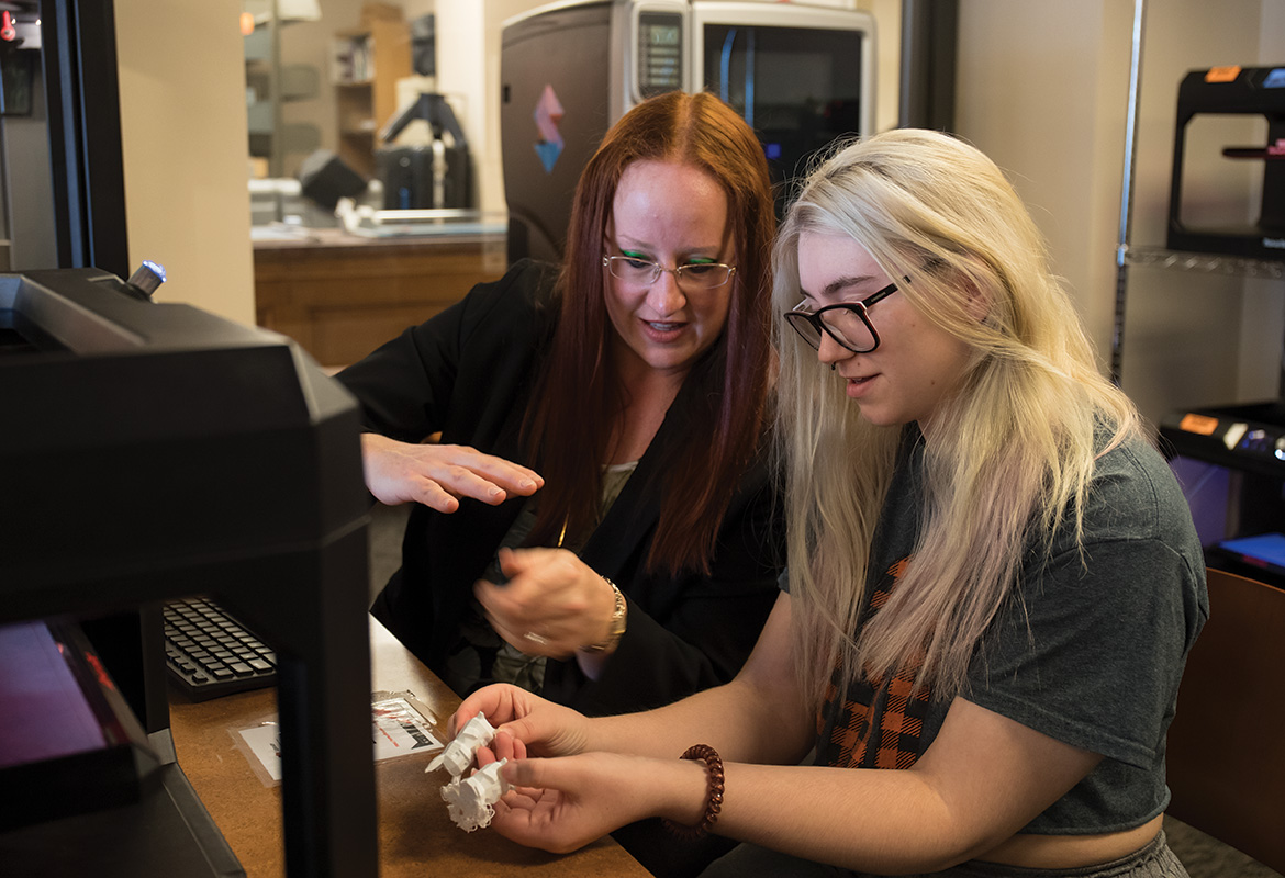 Creative Studios Specialist Shannon Austin guides a student using a 3D printer in the Edmon Low Creative Studios.