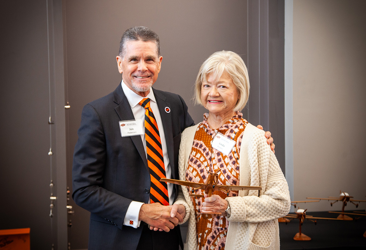 Dean of Education and Human Sciences Jon Pedersen presents Linda Booker with a handcrafted Cirrus SR20 model plane, a gift given to each flight center donor.
