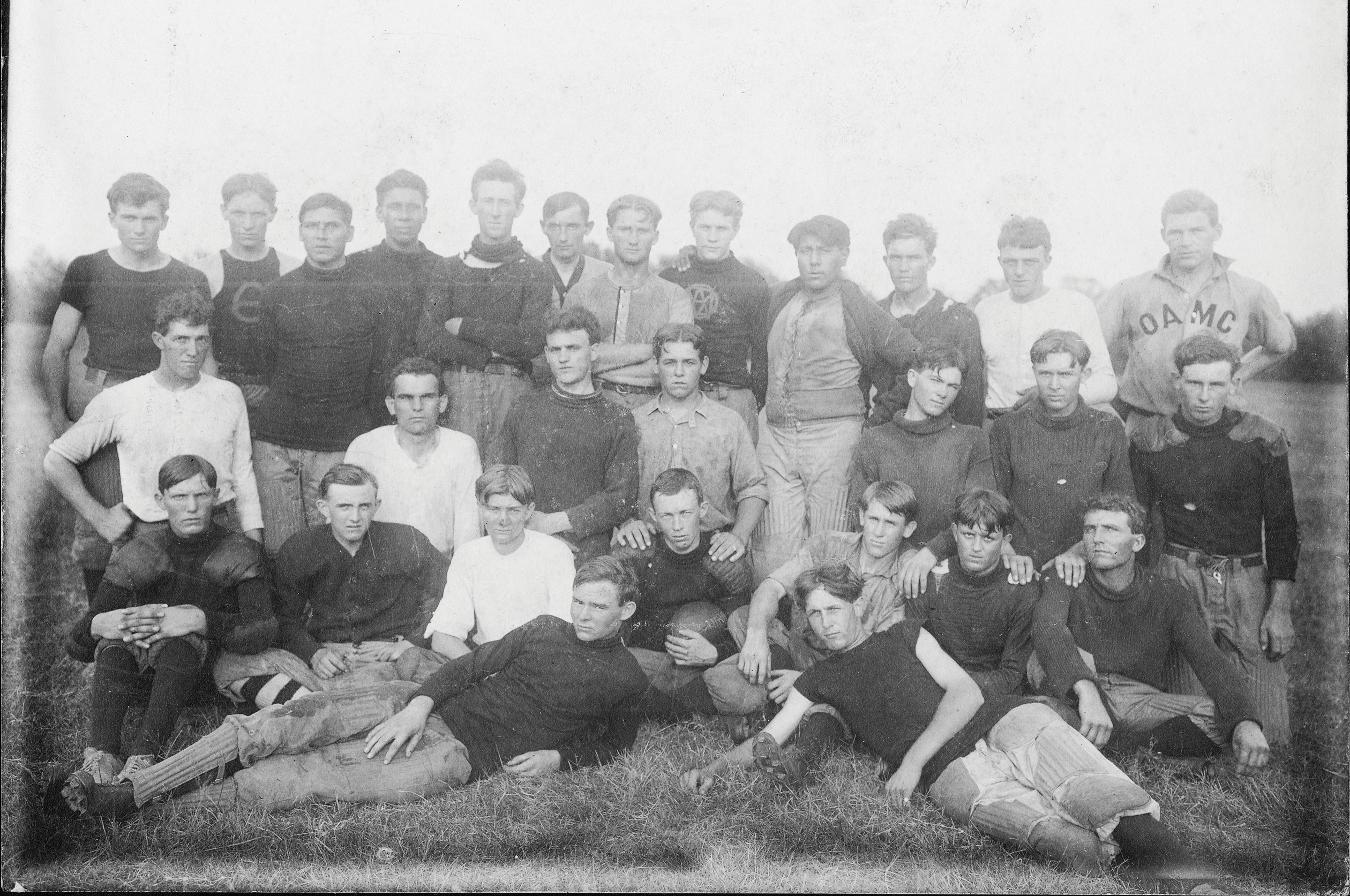 The 1908 football team and practice squad gathers for a picture. Ed Gallagher is on the back row upper left corner, Coach Ed Parry is in the upper right wearing the OAMC shirt and Clark Oursler is in the third row second from the left wearing a white shirt.