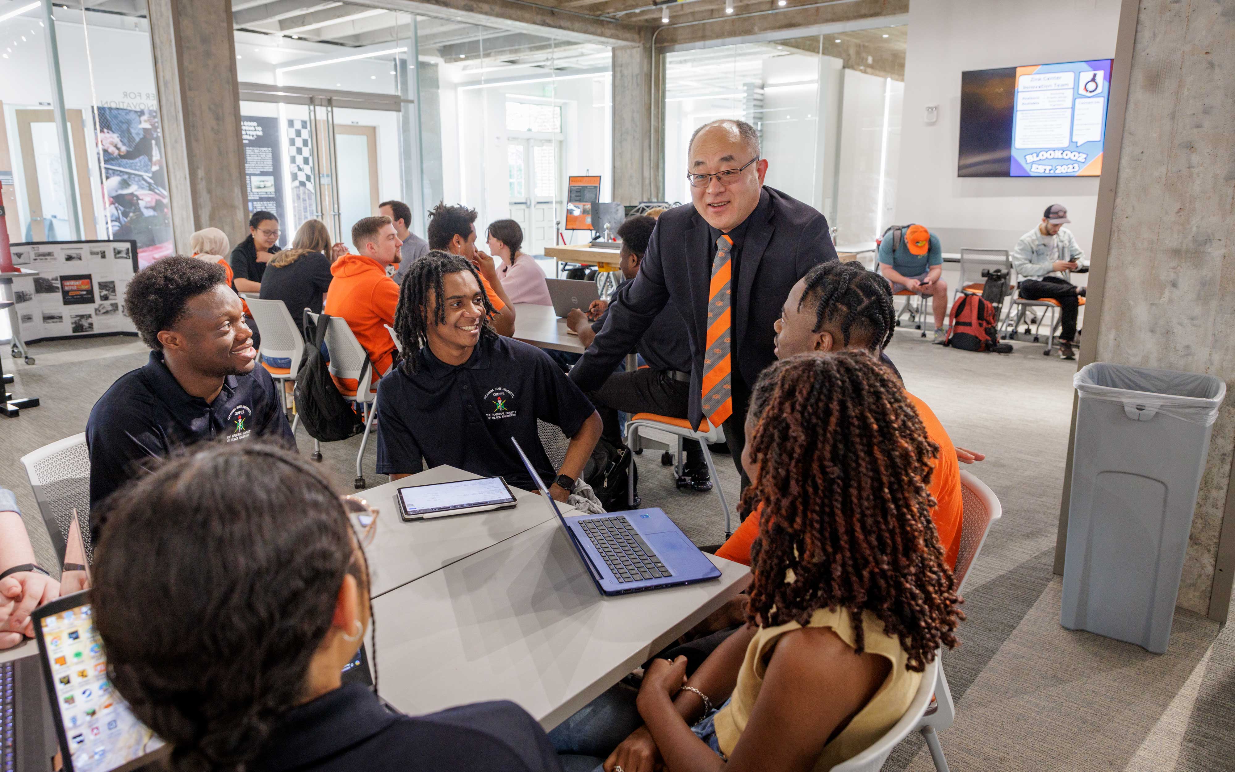 Dr. Hanchen Huang talks to students working on a group project at a table