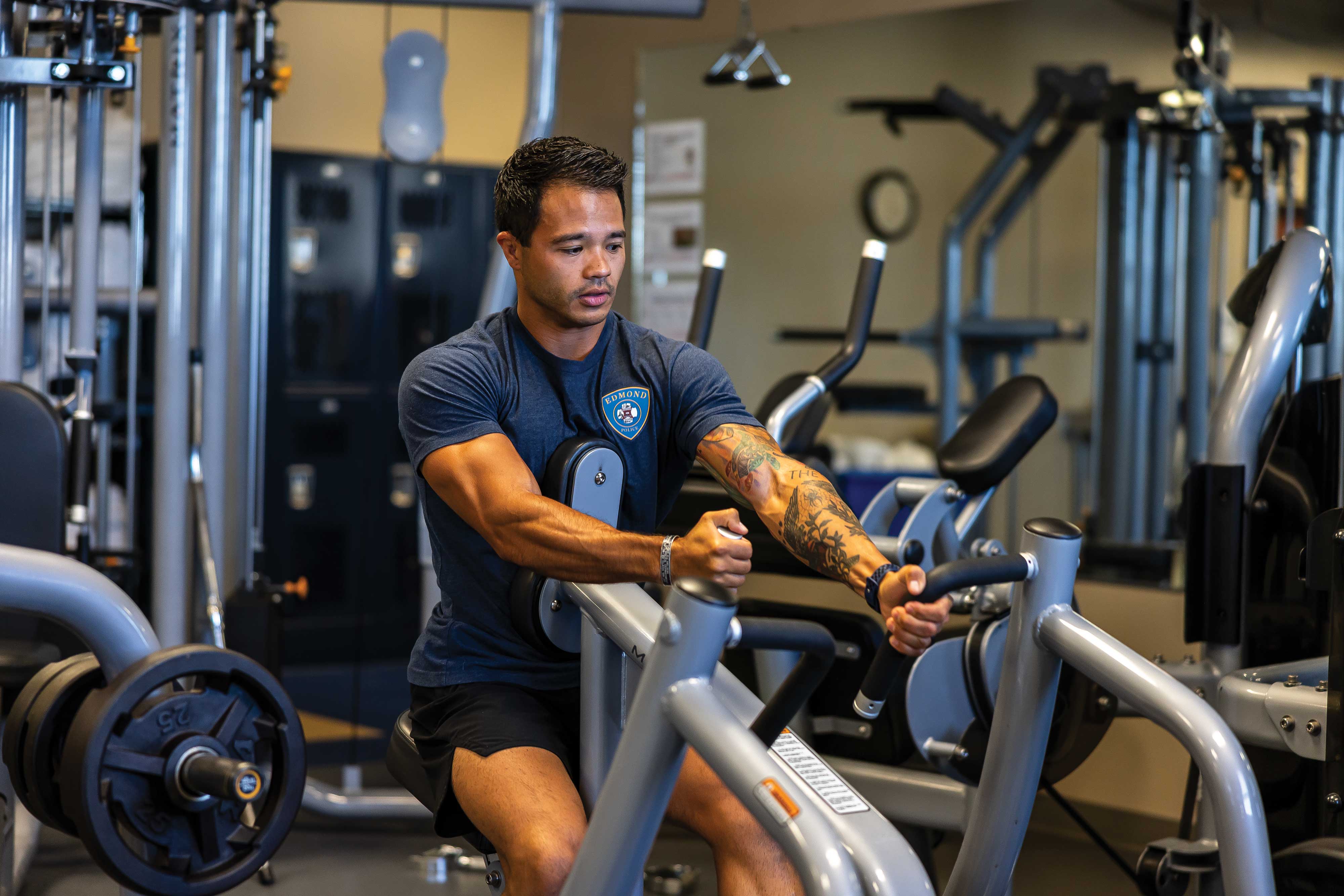 a male police officer wearing workout clothes uses a machine to workout 