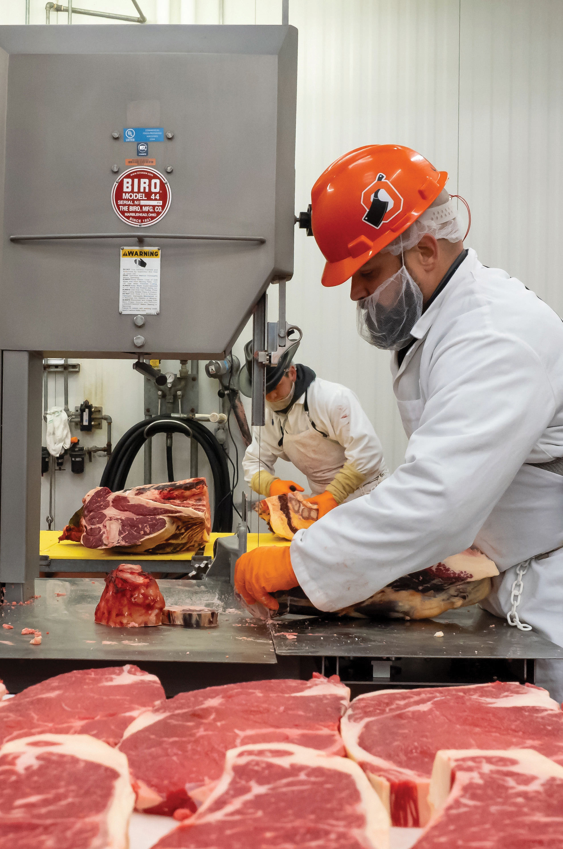 a man in a meat packing facility cuts up steaks