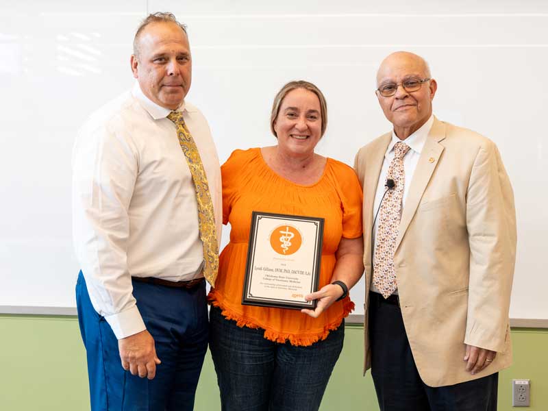 Dr. Lyndi Gilliam receives the 2024 Zoetis Distinguished Veterinary Teaching Award from Dr. Jerry Ritchey, associate dean for academic and student affairs and Dean Dr. Carlos Risco.