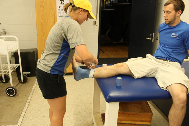 (Left) Emilie Troxell, athletic training senior, practices taping the ankle of fellow OSU athletic training student, Clayton Dir. Troxell is currently working with Stillwater High School as an athletic training assistant.