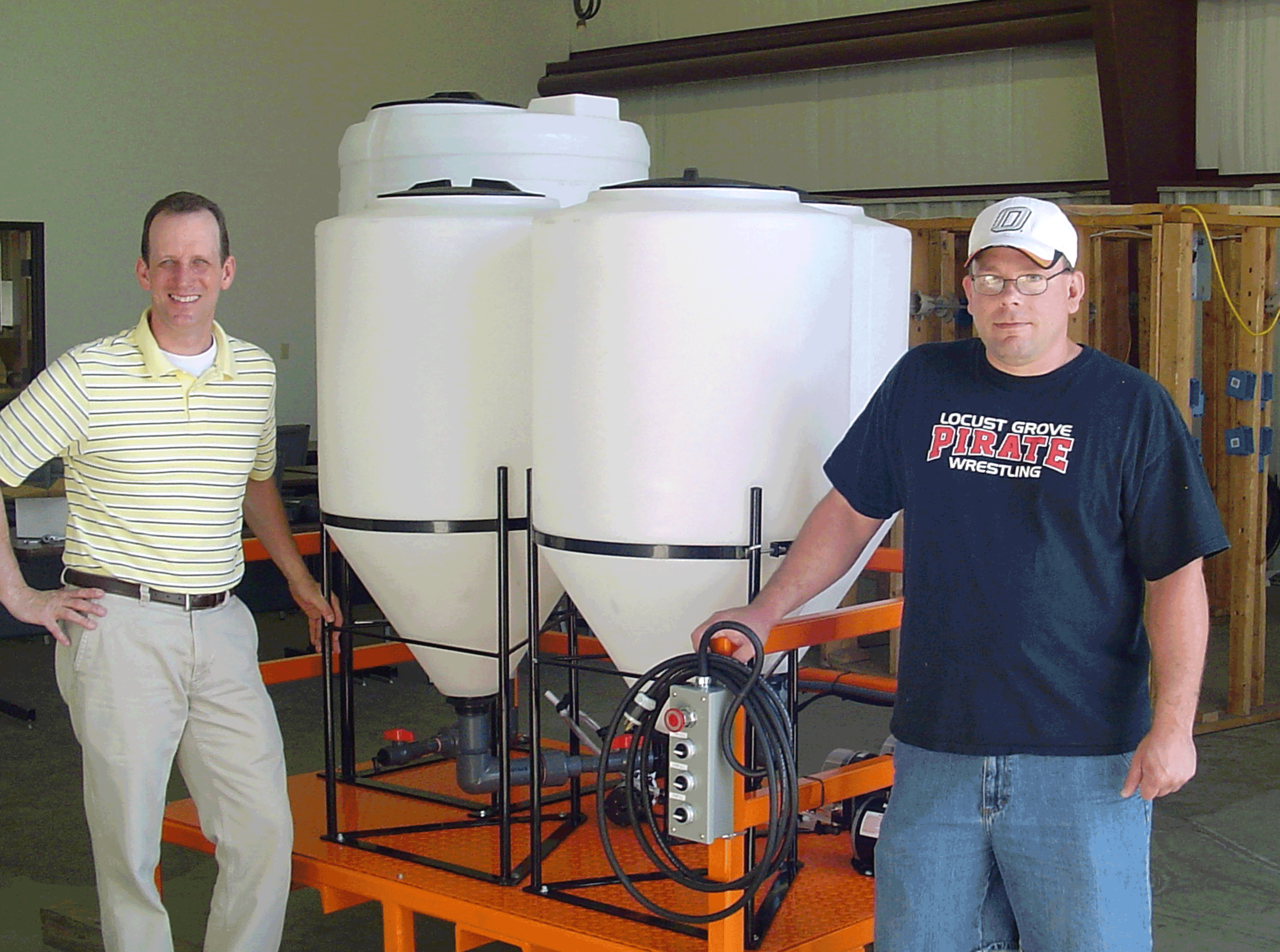 Scott Fry (left), director of workforce development at OSU-IT,  and student Jerrod Estes stand with the processing equipment designed and fabricated by OSU for Cowboy Technologies start-up, AMP.