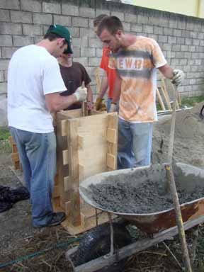 Members of Engineers Without Borders at OSU tamp concrete in a mold that will produce a biosand filter for use in a Honduran village.